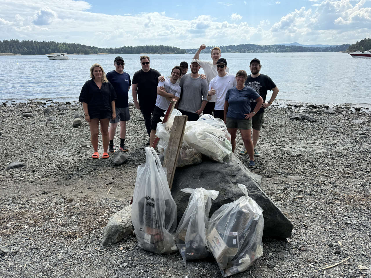 10 people standing on a beach showing the bags of trash collected at the beach